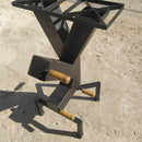 Base metálica preta para mesa com pés quadrados e detalhes em madeira sobre chão de cimento