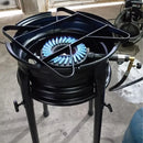 Fogão industrial de gás com queimador aceso e estrutura metálica preta em piso de concreto