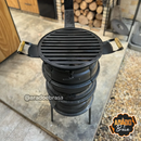 Churrasqueira portátil feita com pneus reciclados, grelha preta com alças de madeira, usada para assar alimentos